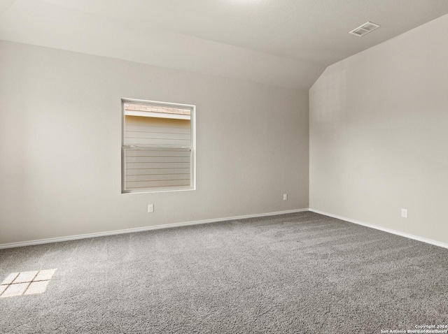 empty room with vaulted ceiling and carpet flooring