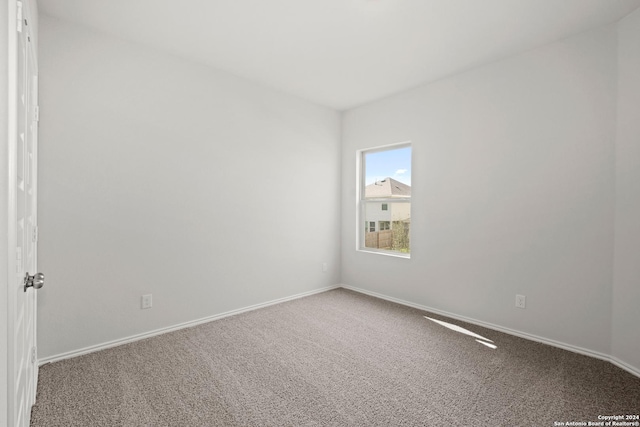 carpeted empty room featuring baseboards