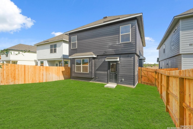 back of house with a lawn and a fenced backyard