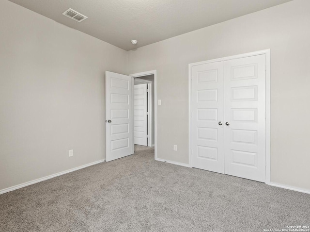 unfurnished bedroom with a closet and light colored carpet