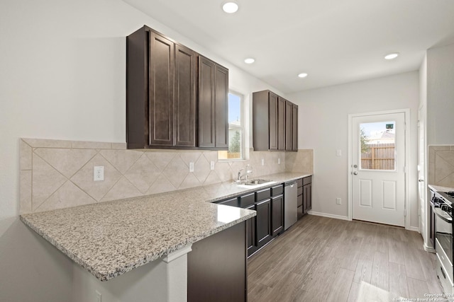 kitchen with dark brown cabinetry, light wood-style flooring, plenty of natural light, and backsplash