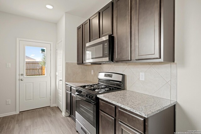 kitchen with tasteful backsplash, stainless steel appliances, hardwood / wood-style flooring, light stone counters, and dark brown cabinetry