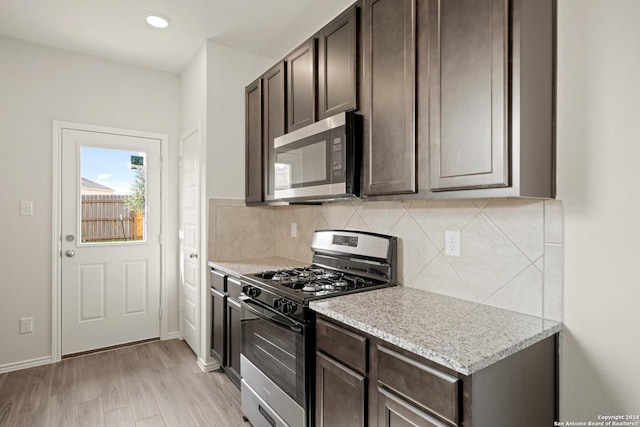 kitchen featuring light wood-style floors, tasteful backsplash, dark brown cabinetry, and appliances with stainless steel finishes