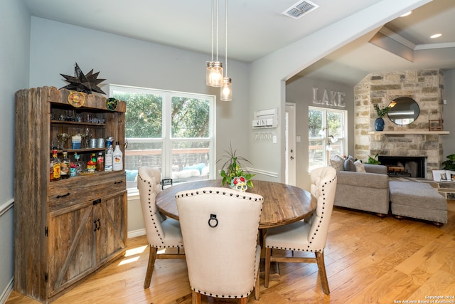 dining room featuring a stone fireplace and light hardwood / wood-style flooring