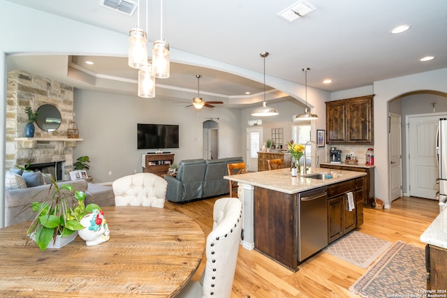 kitchen featuring a fireplace, sink, ceiling fan, appliances with stainless steel finishes, and a center island with sink