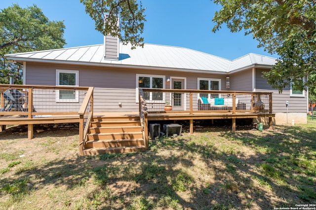 rear view of house featuring a wooden deck and a lawn