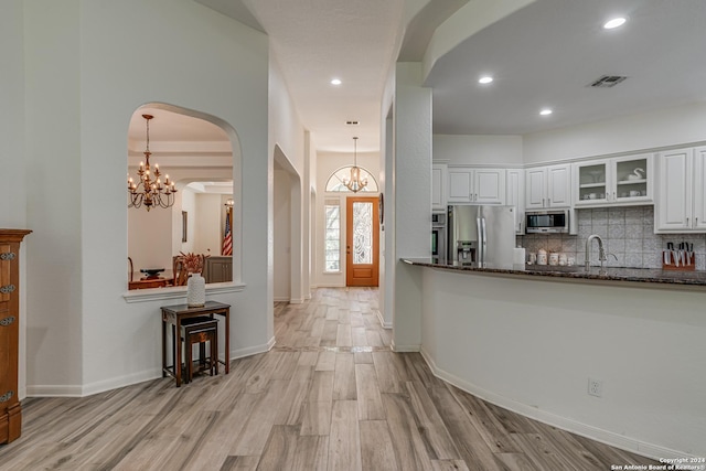 kitchen with arched walkways, visible vents, stainless steel appliances, and an inviting chandelier
