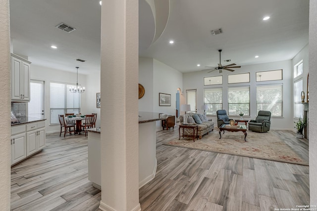 living room featuring ceiling fan with notable chandelier, a healthy amount of sunlight, light wood finished floors, and recessed lighting