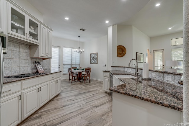 kitchen featuring visible vents, stainless steel gas cooktop, a sink, light wood-style floors, and backsplash