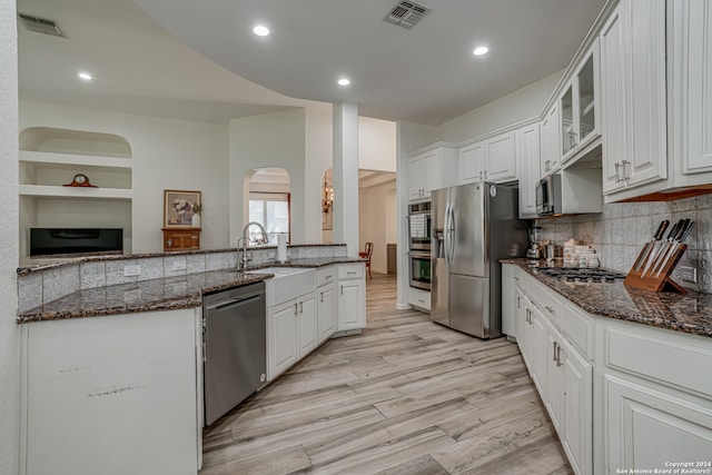 kitchen featuring light wood-type flooring, white cabinets, dark stone countertops, and stainless steel appliances