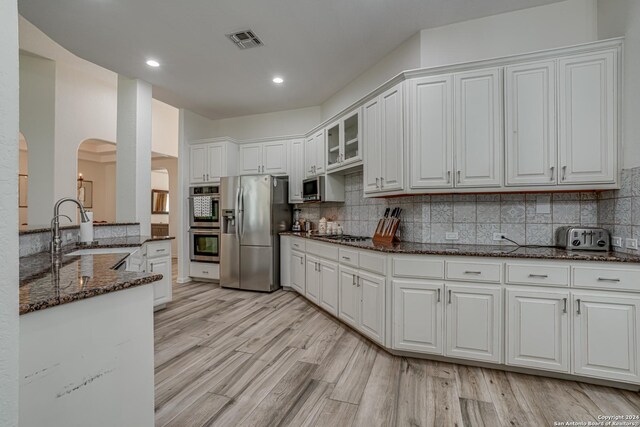 kitchen with visible vents, appliances with stainless steel finishes, arched walkways, a sink, and backsplash