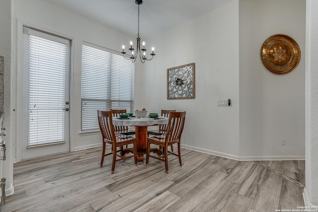 dining space featuring baseboards, a wealth of natural light, light wood-type flooring, and a notable chandelier