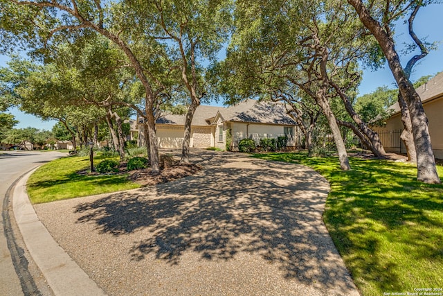 ranch-style house featuring a front lawn, driveway, stucco siding, and a garage