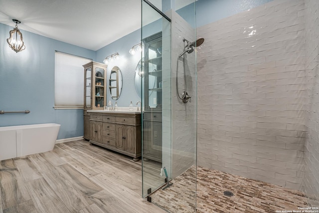 full bathroom with baseboards, wood finished floors, a freestanding tub, vanity, and a walk in shower
