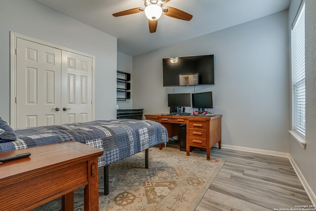 bedroom featuring a closet, light wood finished floors, baseboards, ceiling fan, and lofted ceiling