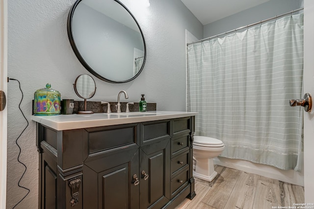 full bath featuring wood finished floors, toilet, vanity, a shower with curtain, and a textured wall