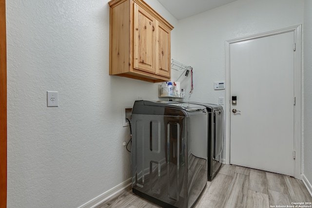 clothes washing area featuring light wood-type flooring, cabinets, and washer and dryer