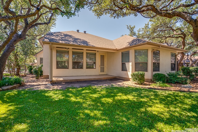 rear view of house featuring a lawn and a patio