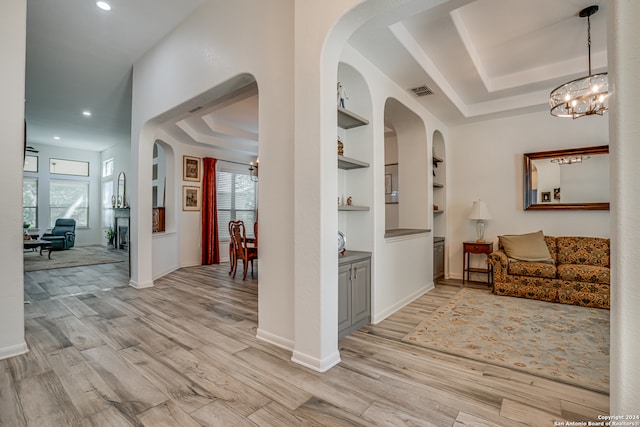 hallway with built in features, plenty of natural light, and light hardwood / wood-style floors