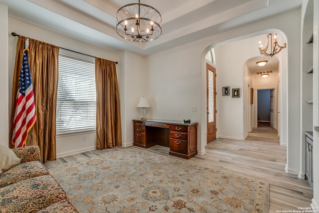 interior space featuring light wood-type flooring, a raised ceiling, and a chandelier