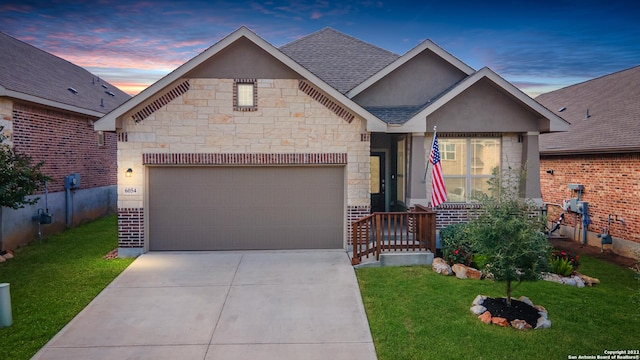 view of front facade with a shingled roof, a garage, a yard, stone siding, and driveway