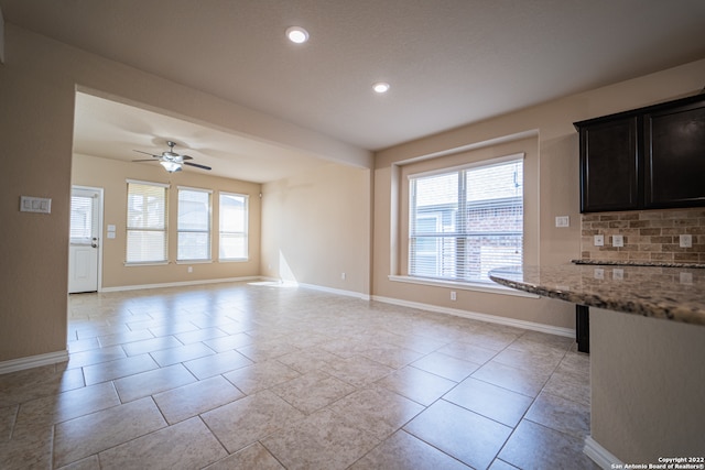 kitchen with ceiling fan, light stone counters, light tile patterned floors, and tasteful backsplash