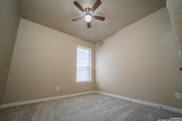 carpeted spare room featuring a textured ceiling, baseboards, ceiling fan, and vaulted ceiling