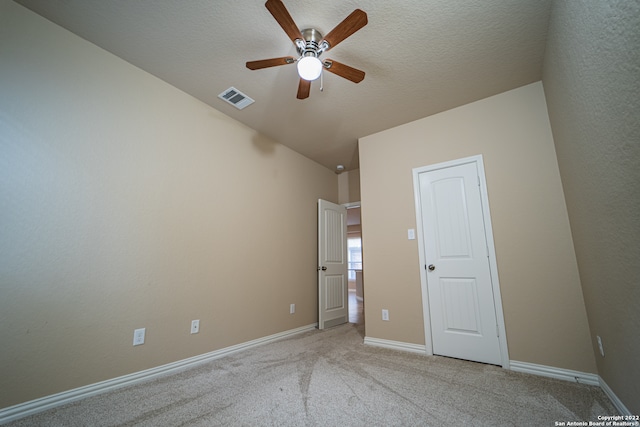 unfurnished bedroom with lofted ceiling, ceiling fan, light carpet, and a textured ceiling