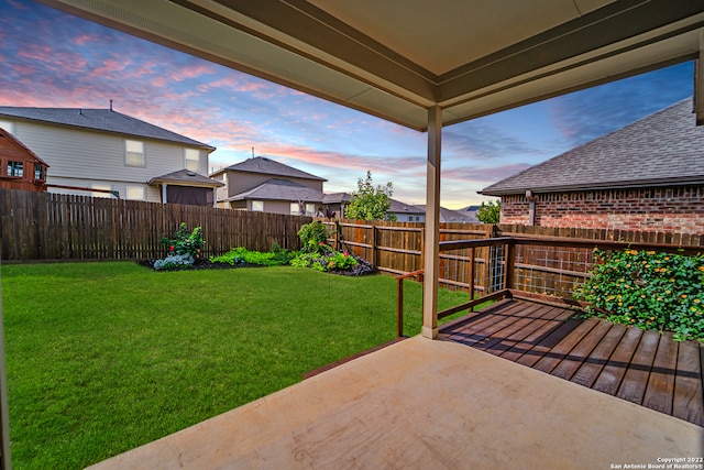 patio terrace at dusk featuring a lawn