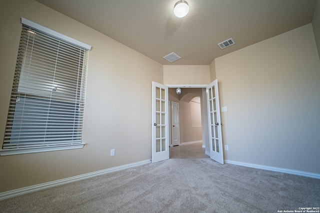 unfurnished bedroom featuring a textured ceiling, carpet, and french doors