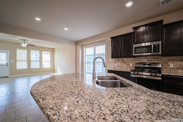 kitchen with appliances with stainless steel finishes, light stone countertops, sink, and ceiling fan