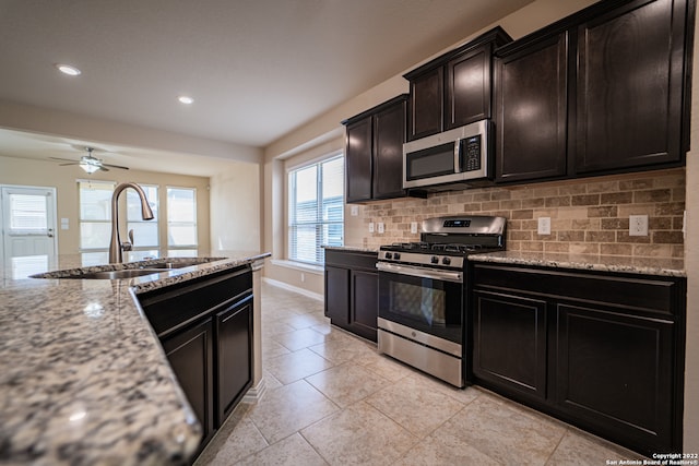 kitchen with light stone countertops, appliances with stainless steel finishes, sink, decorative backsplash, and ceiling fan