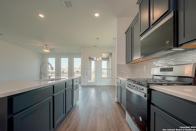 kitchen featuring backsplash, ceiling fan with notable chandelier, sink, hanging light fixtures, and stainless steel range with gas stovetop