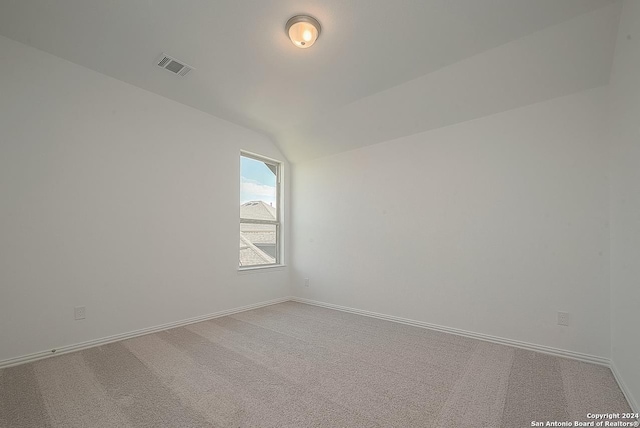 empty room featuring carpet and vaulted ceiling