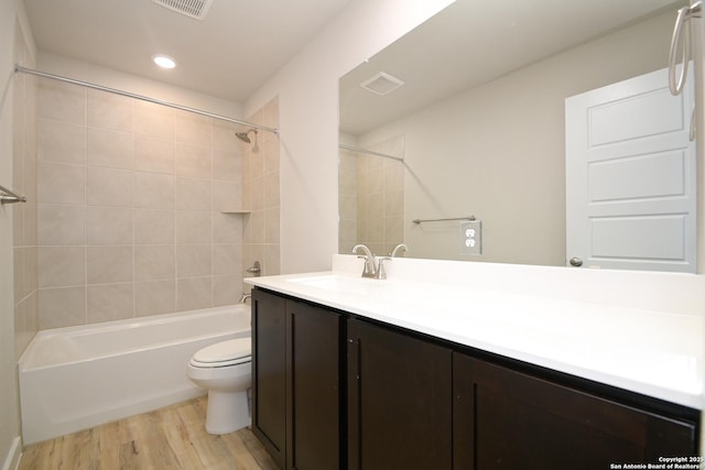 full bathroom with vanity, hardwood / wood-style flooring, toilet, and tiled shower / bath