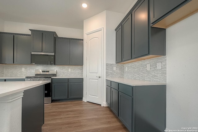 kitchen featuring tasteful backsplash, gray cabinetry, dark wood-type flooring, and stainless steel range oven