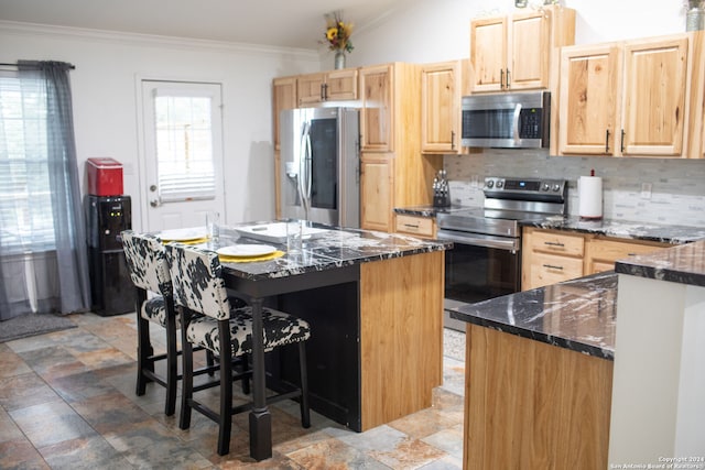 kitchen featuring a center island, stainless steel appliances, light brown cabinets, and a breakfast bar area