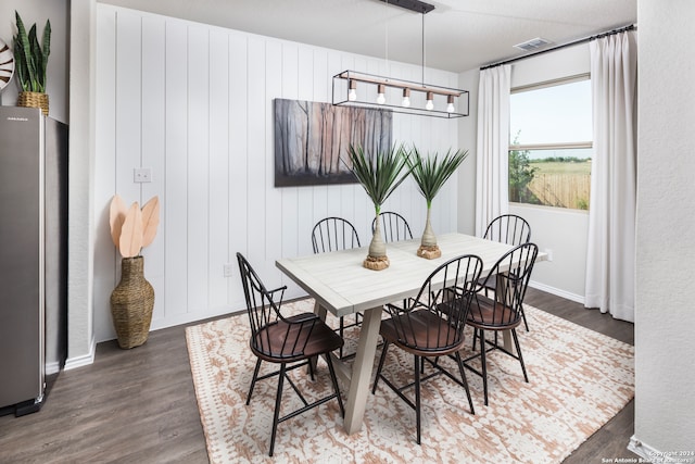 dining area featuring wooden walls and dark wood-type flooring