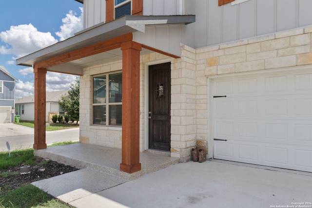 doorway to property with covered porch and a garage