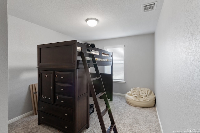 bedroom with light carpet and a textured ceiling