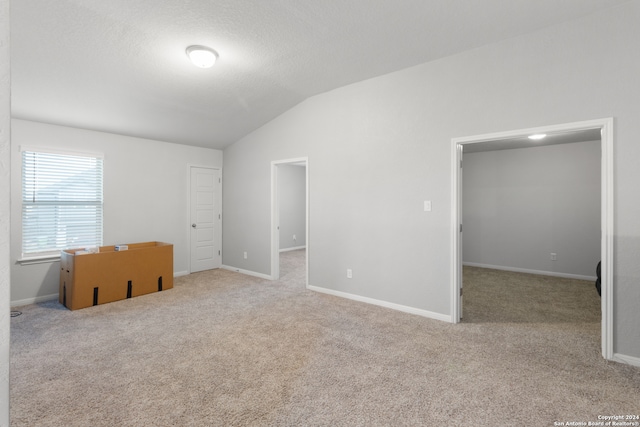 carpeted empty room with a textured ceiling and vaulted ceiling