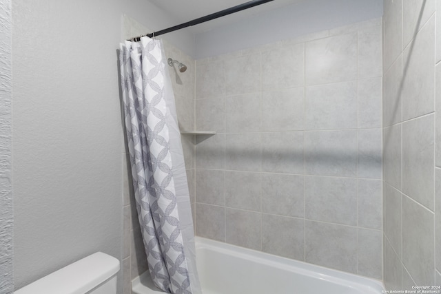 bathroom featuring toilet and shower / tub combo with curtain