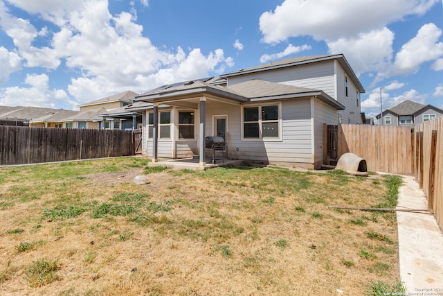 rear view of house featuring a lawn and a patio