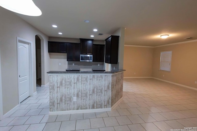 8446 Buckhorn Parke, San Antonio, TX 78254 - kitchen with arched walkways, dark cabinets, dark stone countertops, and stainless steel microwave