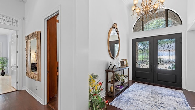 foyer with dark wood-type flooring, a chandelier, a high ceiling, and french doors