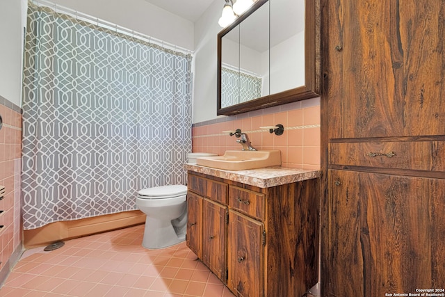 bathroom with tile walls, toilet, vanity, and tile patterned flooring