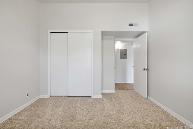 unfurnished bedroom with a closet, electric panel, and carpet flooring