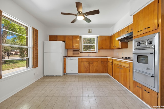 kitchen with decorative backsplash, plenty of natural light, sink, and white appliances