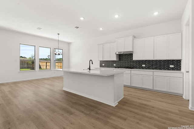 kitchen featuring white cabinets, light wood-type flooring, and a center island with sink