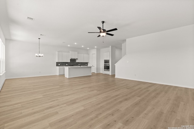 unfurnished living room with light hardwood / wood-style flooring and ceiling fan with notable chandelier